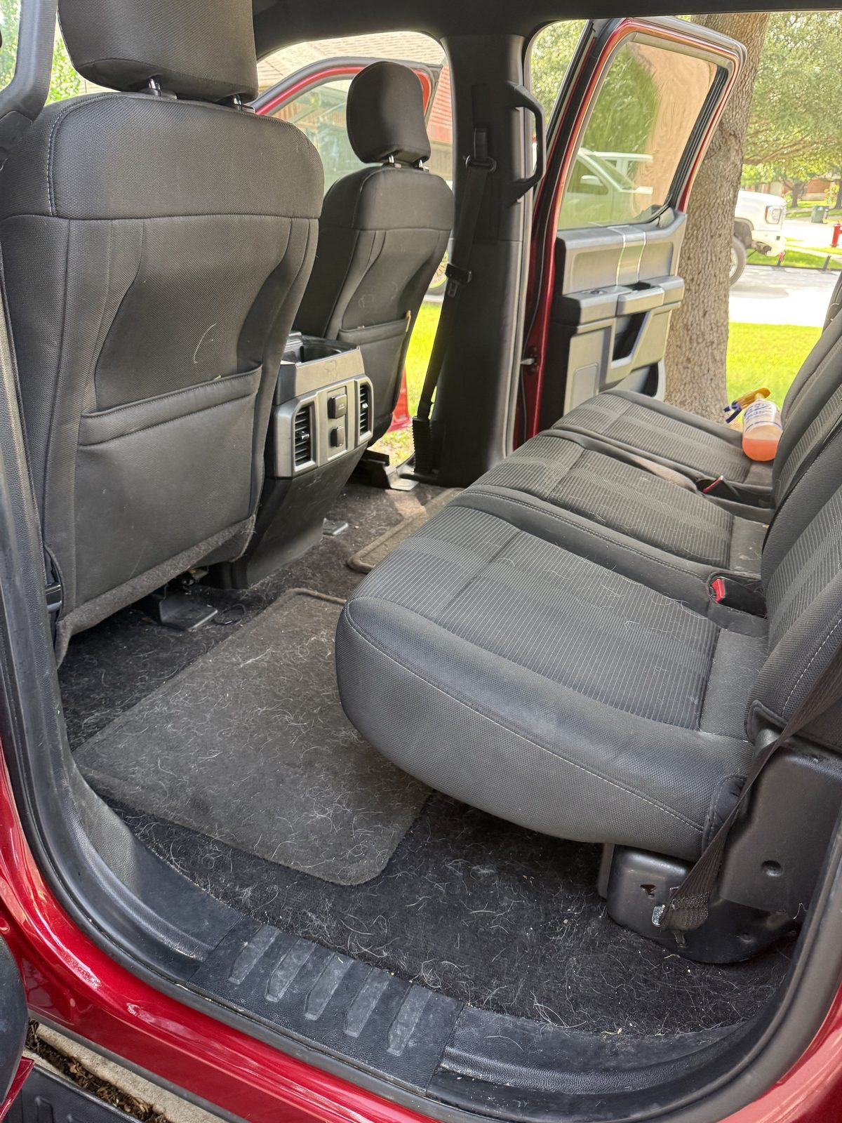 Truck rear driver-side seats and carpet, dirty and covered in pet hair before detailing